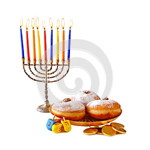 image of jewish holiday Hanukkah with menorah (traditional Candelabra), donuts and wooden dreidels (spinning top).isolated