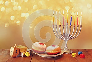 image of jewish holiday Hanukkah with menorah (traditional Candelabra), donuts and wooden dreidels (spinning top)