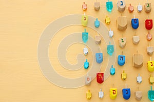 Image of jewish holiday Hanukkah with wooden dreidels colection & x28;spinning top& x29; over pastel yellow background.