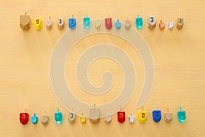 Image of jewish holiday Hanukkah with wooden dreidels colection & x28;spinning top& x29; over pastel yellow background.