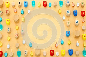 Image of jewish holiday Hanukkah with wooden dreidels colection & x28;spinning top& x29; over pastel yellow background.
