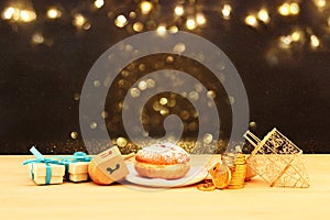 Image of jewish holiday Hanukkah with wooden dreidels & x28;spinning top& x29; and donut on the table.