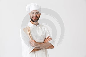 Image of joyful chief man in cook uniform smiling while holding wooden kitchen utensils
