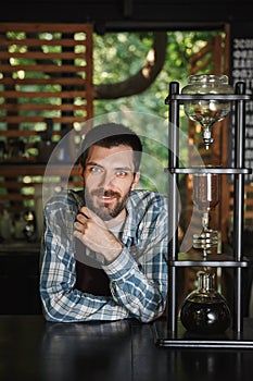 Image of joyous barista boy making coffee while working in cafe or coffeehouse outdoor