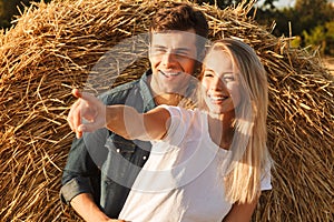 Image of joyous couple man and woman walking on golden field aft