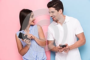 Image of joyous couple using smartphones together, isolated over