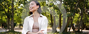 Image of korean girl walking in park, smiling while having a mindful walk in woods