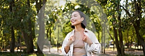 Image of korean girl walking in park, smiling while having a mindful walk in woods