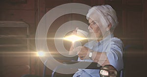 Image of light moving over senior caucasian woman in wheelchair drinking coffee