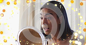 Image of light spots over biracial woman applying make-up