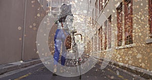 Image of light spots over biracial woman walking with bicycle