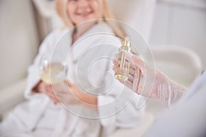Image of little bootle with skin face serum in cosmetologist hand