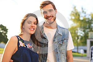 Image of lovely happy couple in summer clothes smiling and holding hands together while walking through city street