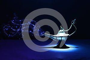 Image of magical mysterious aladdin lamp with glitter smoke. Dark background and dramatic light