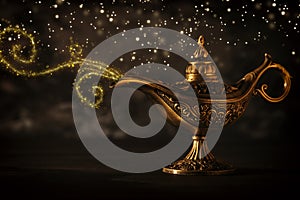 Image of magical mysterious aladdin lamp with glitter sparkle smoke over black background. Lamp of wishes.