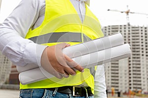 Image of male construction engineer with rolled blueprints at bu