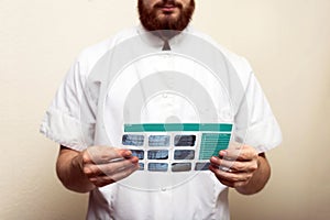 Image of male doctor or dentist holding and looking at old dental x-ray, analyzing