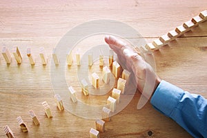 Image of male hand stopping the domino effect. retro style image executive and risk control concept. photo