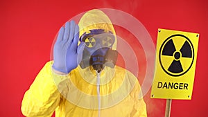 Image of a man in a chemical yellow suit, wearing a protective mask and glasses with a sign of radioactive danger. In