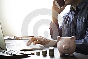 Image of man hand using keyboard of laptop computer with pink piggy bank for account save money.