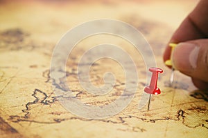 Image man& x27;s hand attached pins to a map, showing location or travel destination. selective focus.