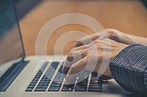Image of man`s hands typing on laptop keyboard.
