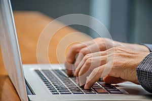 Image of man`s hands typing on laptop keyboard.