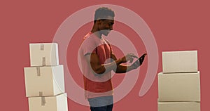 Image of man using tablet with stacks of boxes on red background