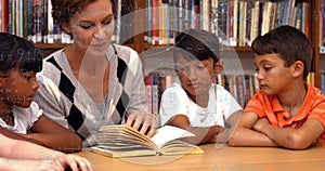 Image of math formulas over happy caucasian female teacher and diverse children reading book