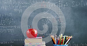 Image of mathematical equations floating over books, apple and coloured pencils with blackboard in t