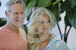 Image of a mature man and younger wife smiling off camera