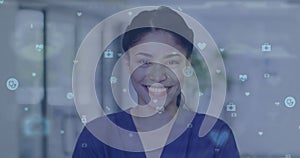 Image of medical icons over portrait of smiling biracial female doctor in hospital corridor