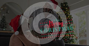 Image of merry christmas text over senior african american couple wearing santa hats