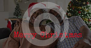 Image of merry christmas text over senior african american couple wearing santa hats