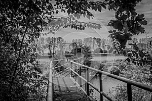 Image of a metal bridge with a closed gate forbidding passage in the middle of the vegetation