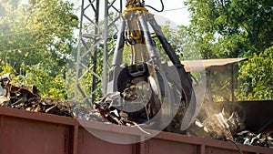 Image of metal gripper crushing and destroying old metal pieces on junkyard