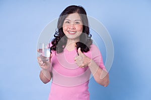 Image of middle aged Asian woman drinking water on blue background