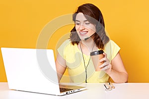 Image of miling freelance operator working online with headsets and laptop computer at office or home. Cheerful call center female