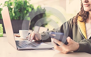 Image of a millennial girl working with laptop and smartphone at the table