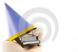 Image of miniature piano paper hat hand white background