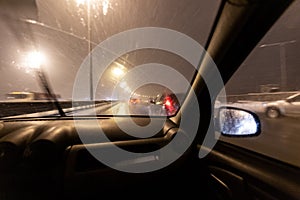 Image with motion blurred effect.Cars fast drive on the winter speedway or highway with roadway lighting in a snow storm