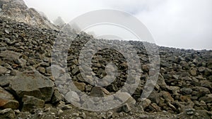 In this image is the mountain slop . many stones are lay the down of mountain.