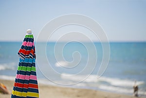 Image of a multicolor beach umbrella closed with the sea photo