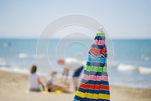 Image of a multicolor sun umbrella closed with people