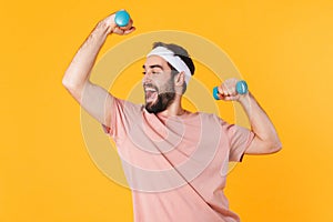 Image of muscular athletic young man having fun and lifting dumbbells