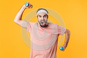 Image of muscular athletic young man having fun and lifting dumbbells