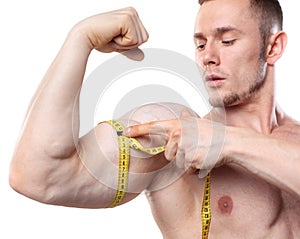 Image of muscular man measure his biceps with measuring tape in centimeters. Isolated on white backgound photo