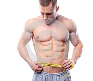 Image of muscular man measure his waist with measuring tape in centimeters. Shot isolated on white background