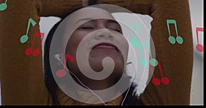 Image of music notes over biracial woman using earphones in city