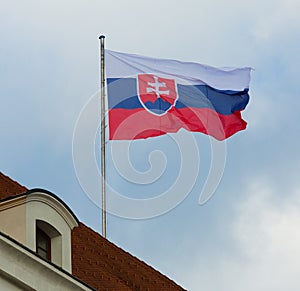 National flag of slovakia waving against blue sky at roof